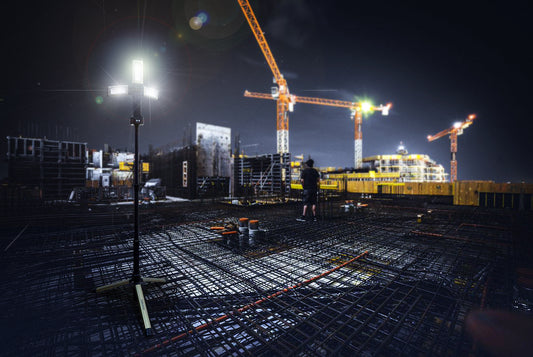 industrial construction night scene featuring a TRi-Mobile in the foreground and a crane in the background.