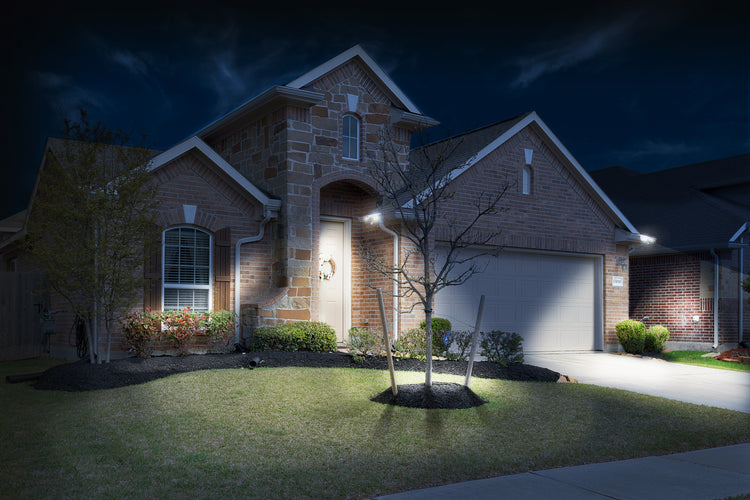 Brick home lit up at night a couple EZ Solar Gutter Light by STKR