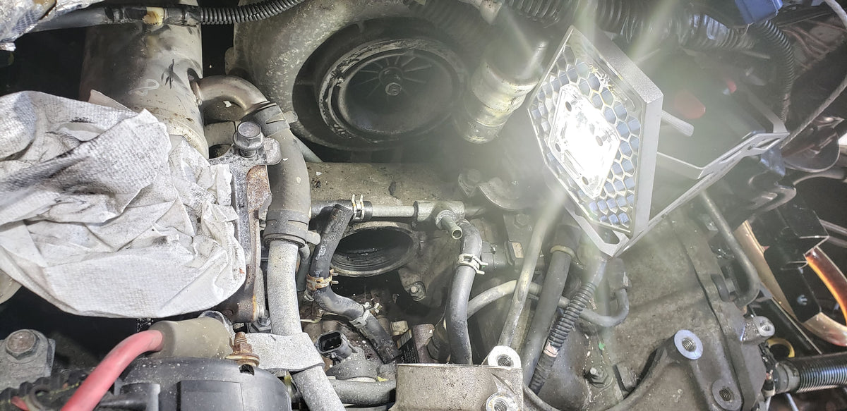 Close-up of a car engine with various components and wiring lit up by a Mobile Task Light