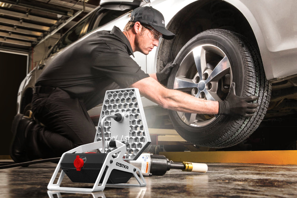 technician removing a tire from a vehicle on a lift lit up by a Mobile Task Light