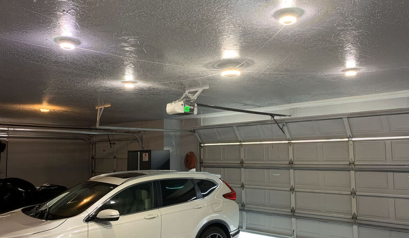 Garage with a white SUV parked inside, ceiling lights, and a closed garage door.