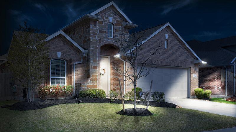 Brick and stone home. nighttime setting. gutter lights lighting up yard and driveway